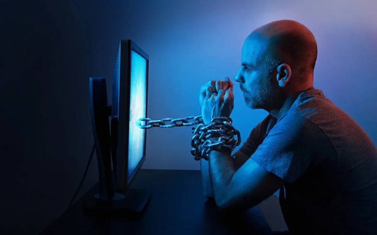Homem acorrentado a uma tela de computador, símbolo do vício em redes sociais